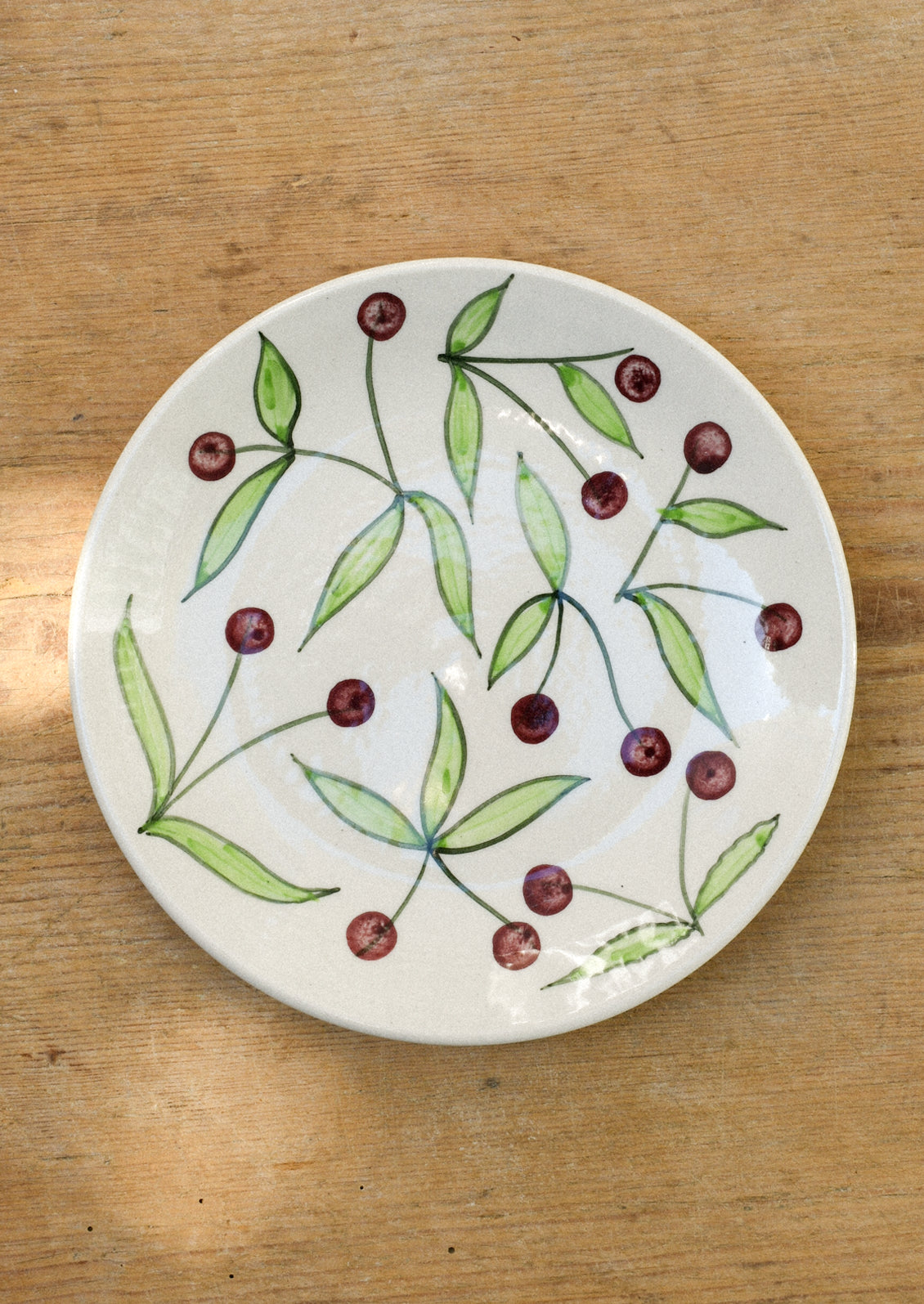 A ceramic plate with illustrated black cherries.