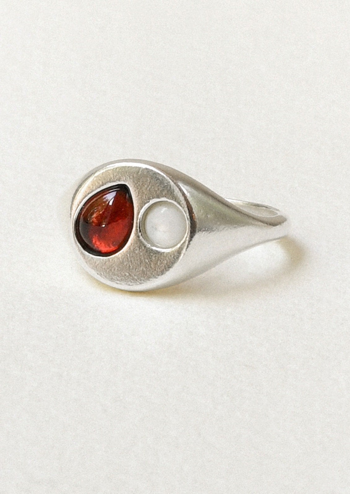 A sterling silver signet ring with a garnet gem and mother of pearl in the center.