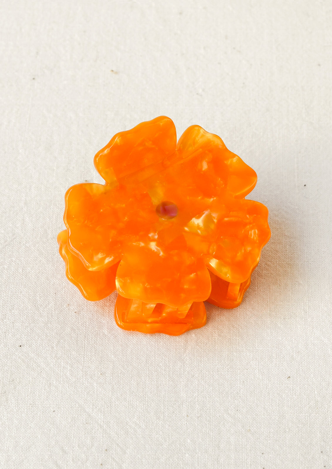 A hair claw depicting an orange marigold flower.