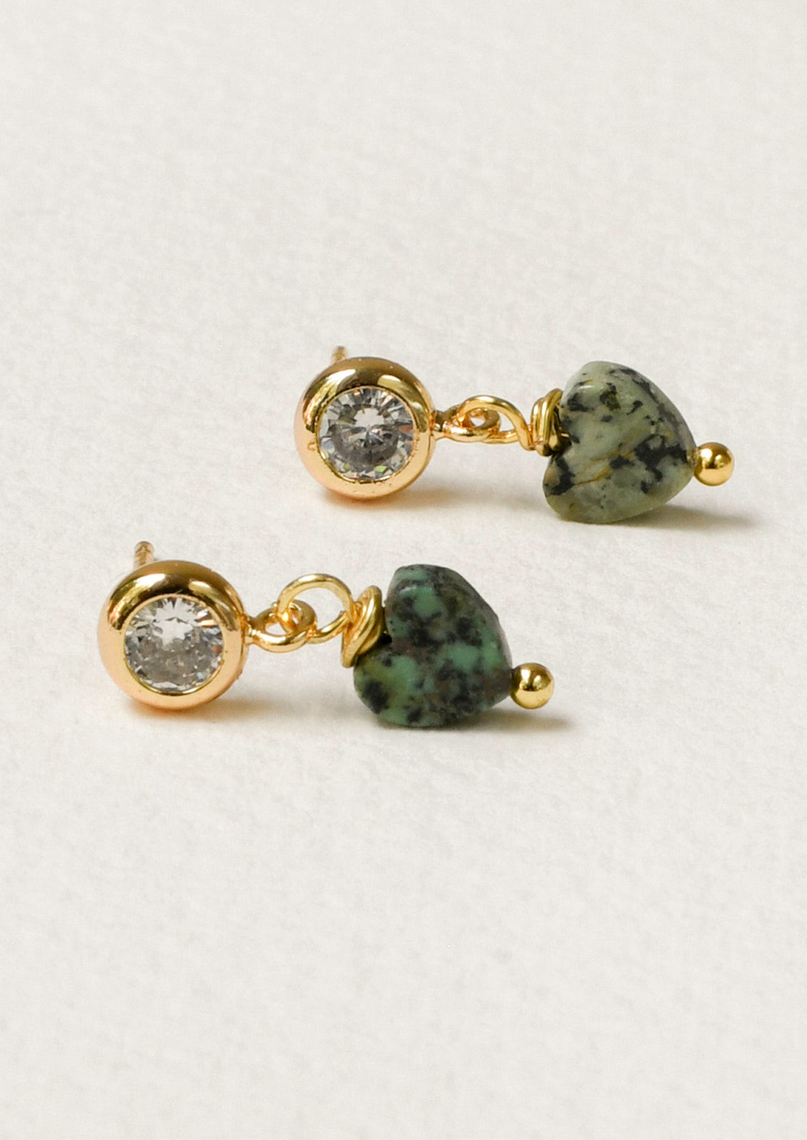 A pair of gold stud earrings with a bezeled cubic zirconia and a dangling heart shaped African turquoise gem.