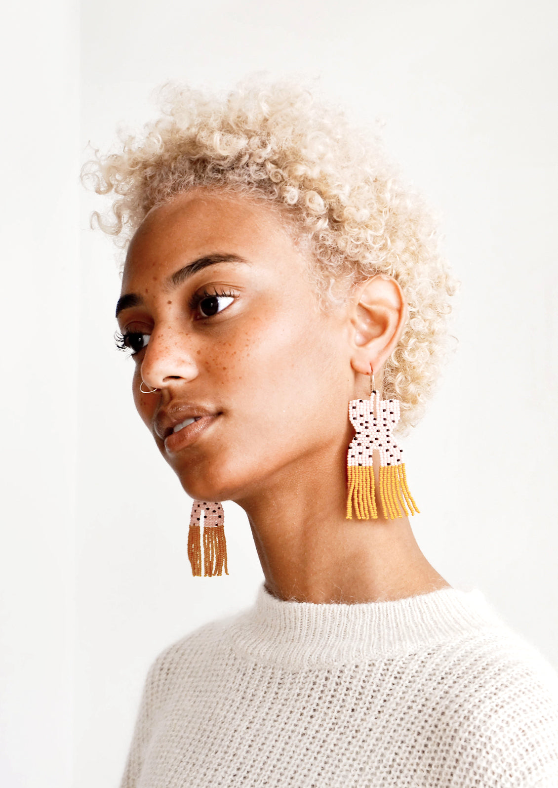 Model wears pink and yellow fringe beaded earrings.