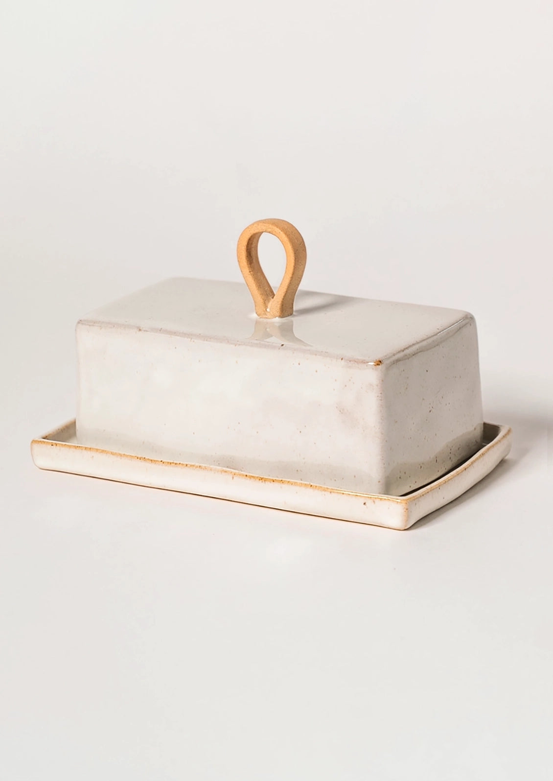 White ceramic butter dish with raw ceramic handle on a beige background