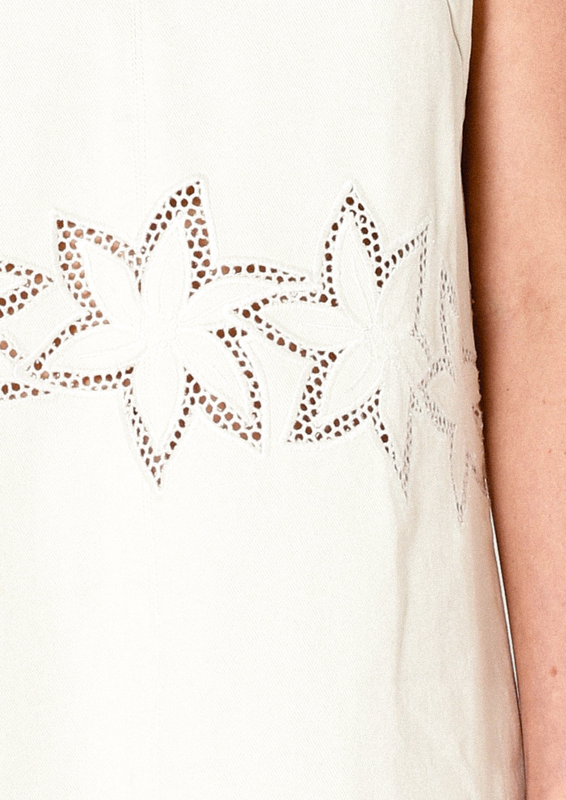 Close-up of a white sleeveless top with star-shaped cutouts.