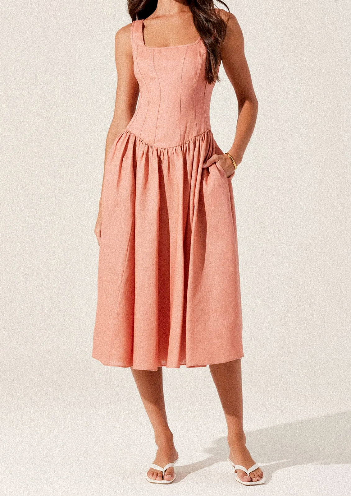 A woman wearing a peach colored corset bodice dress with full skirt.