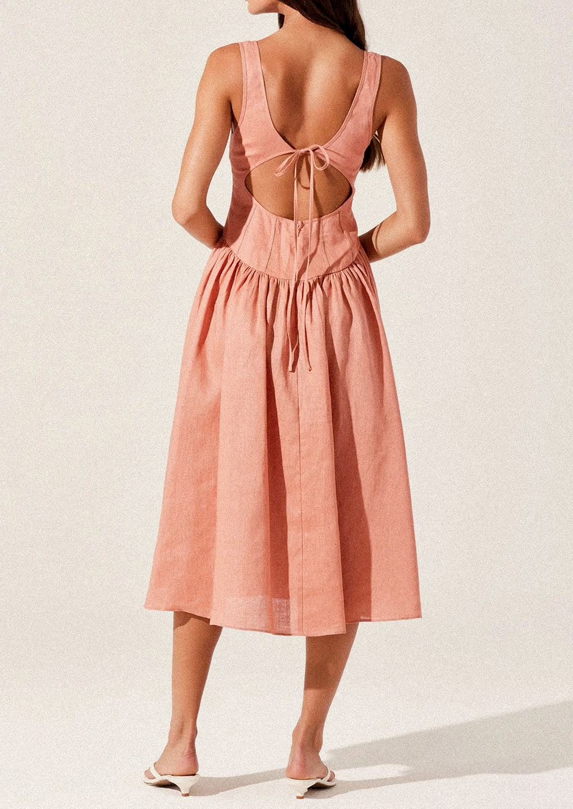 A woman wearing a peach colored corset bodice dress with full skirt.
