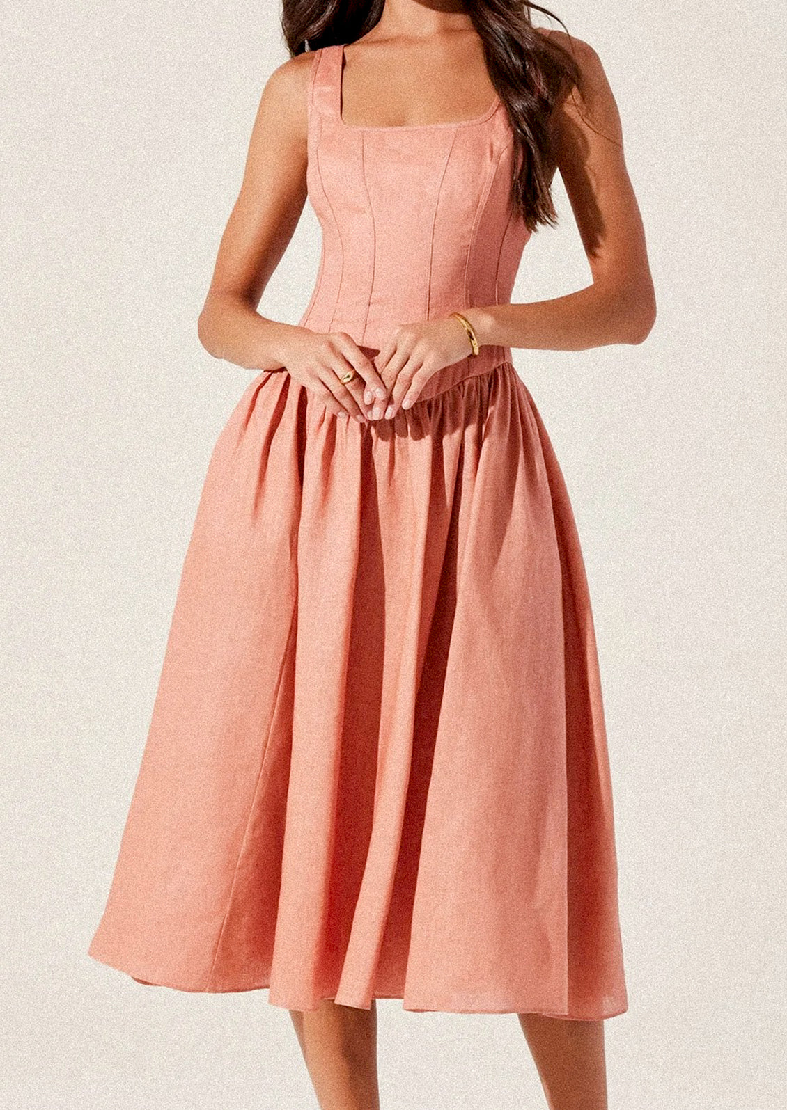 A woman wearing a peach colored corset bodice dress with full skirt.