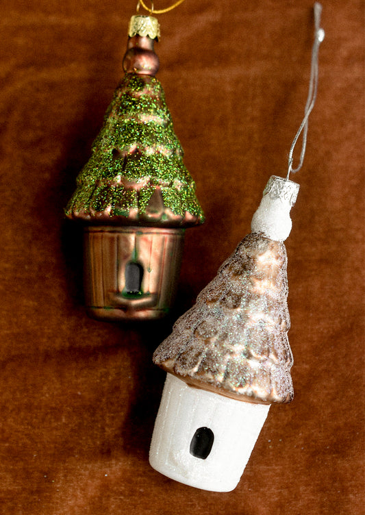 Glass ornaments depicting birdhouses, in white and brown color options.