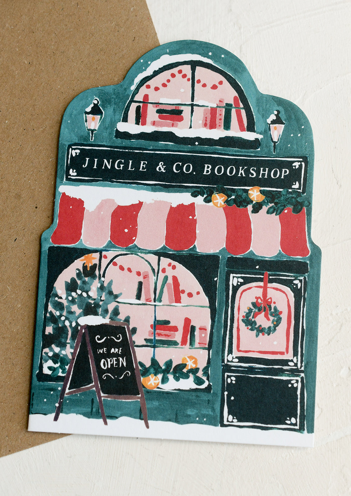 A diecut card in the shape of a bookshop decked out for the holidays.