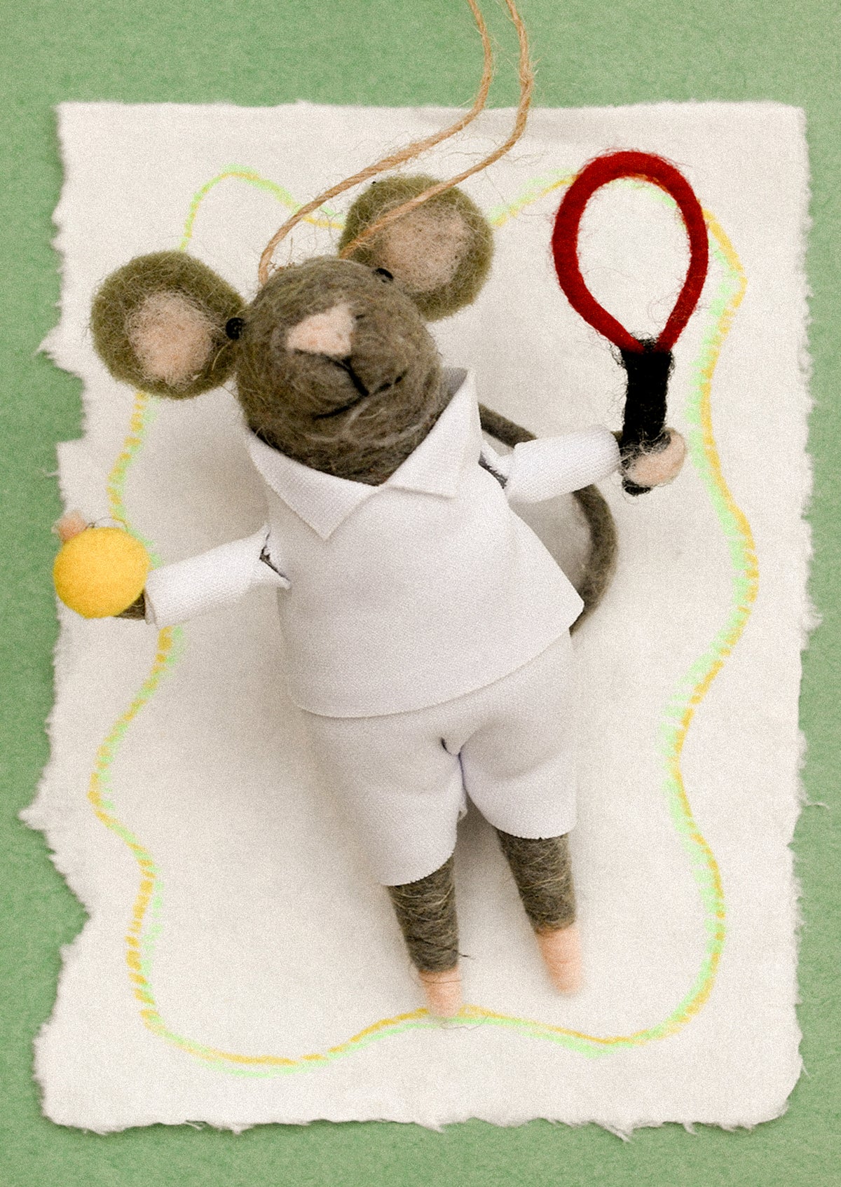 A felted mouse ornament dressed in a tennis outfit and holding a racket and ball.