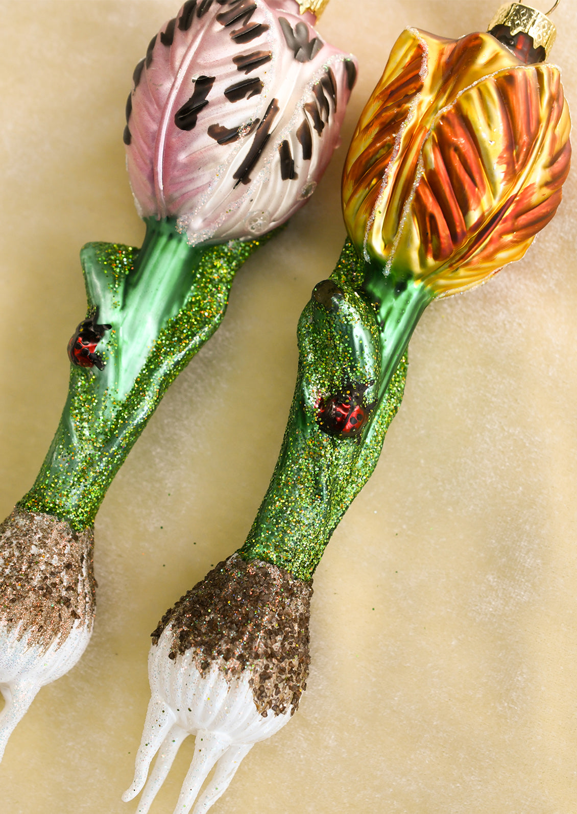 Glass ornaments depicting tulip bulbs with ladybug detail, in assorted colors.