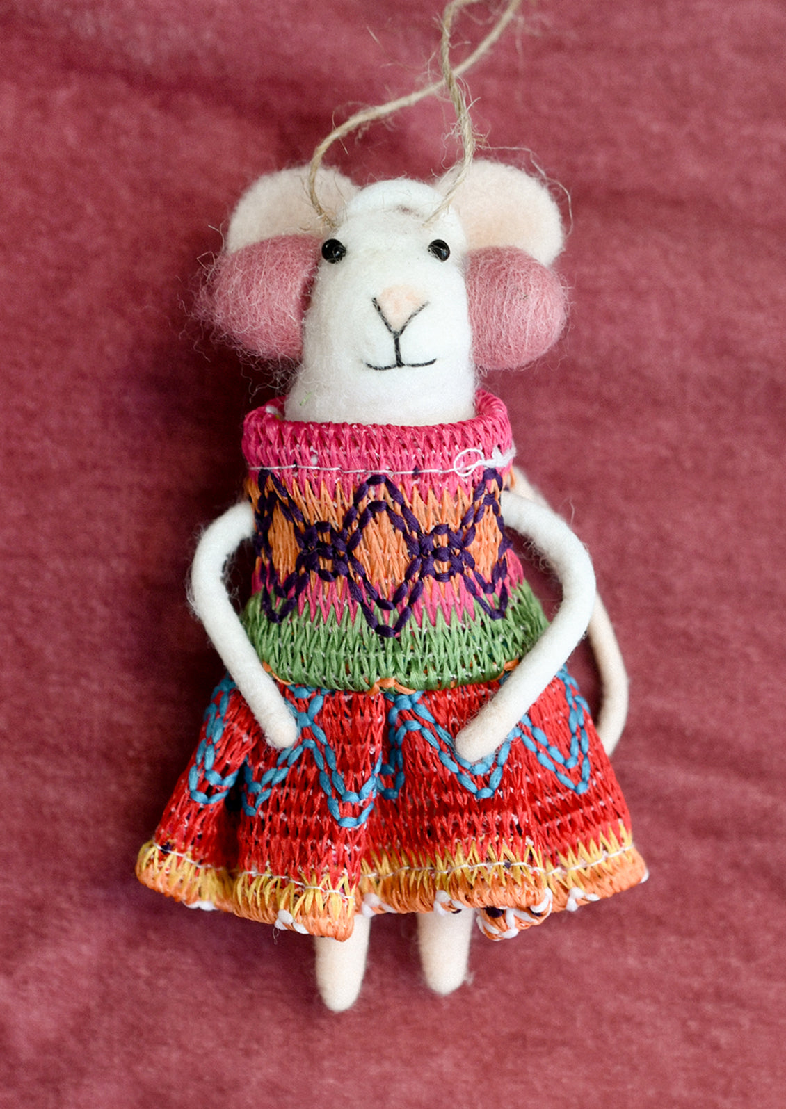 A felted mouse ornament wearing a knit dress and earmuffs.