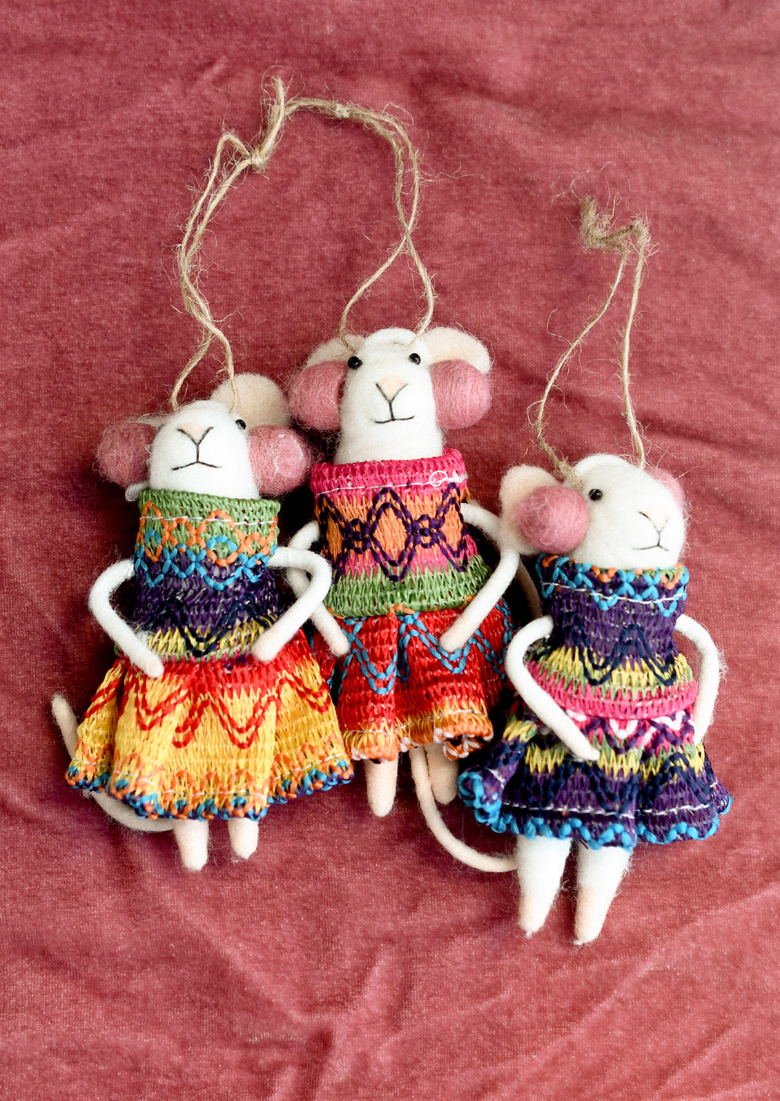 Felted mouse ornaments wearing knit dresses in assorted colors and pink earmuffs.