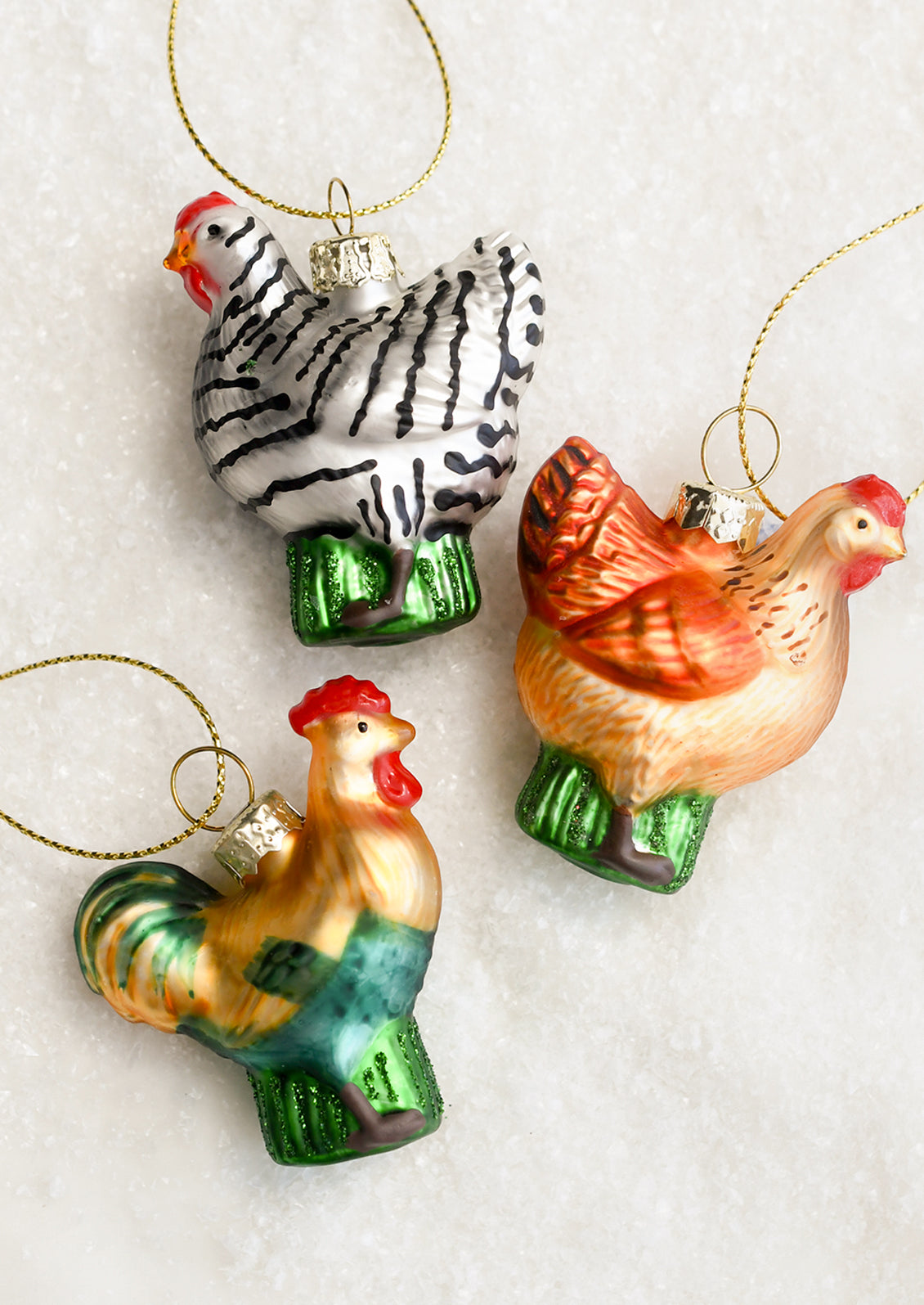 Small glass ornaments depicting chickens in assorted colors.