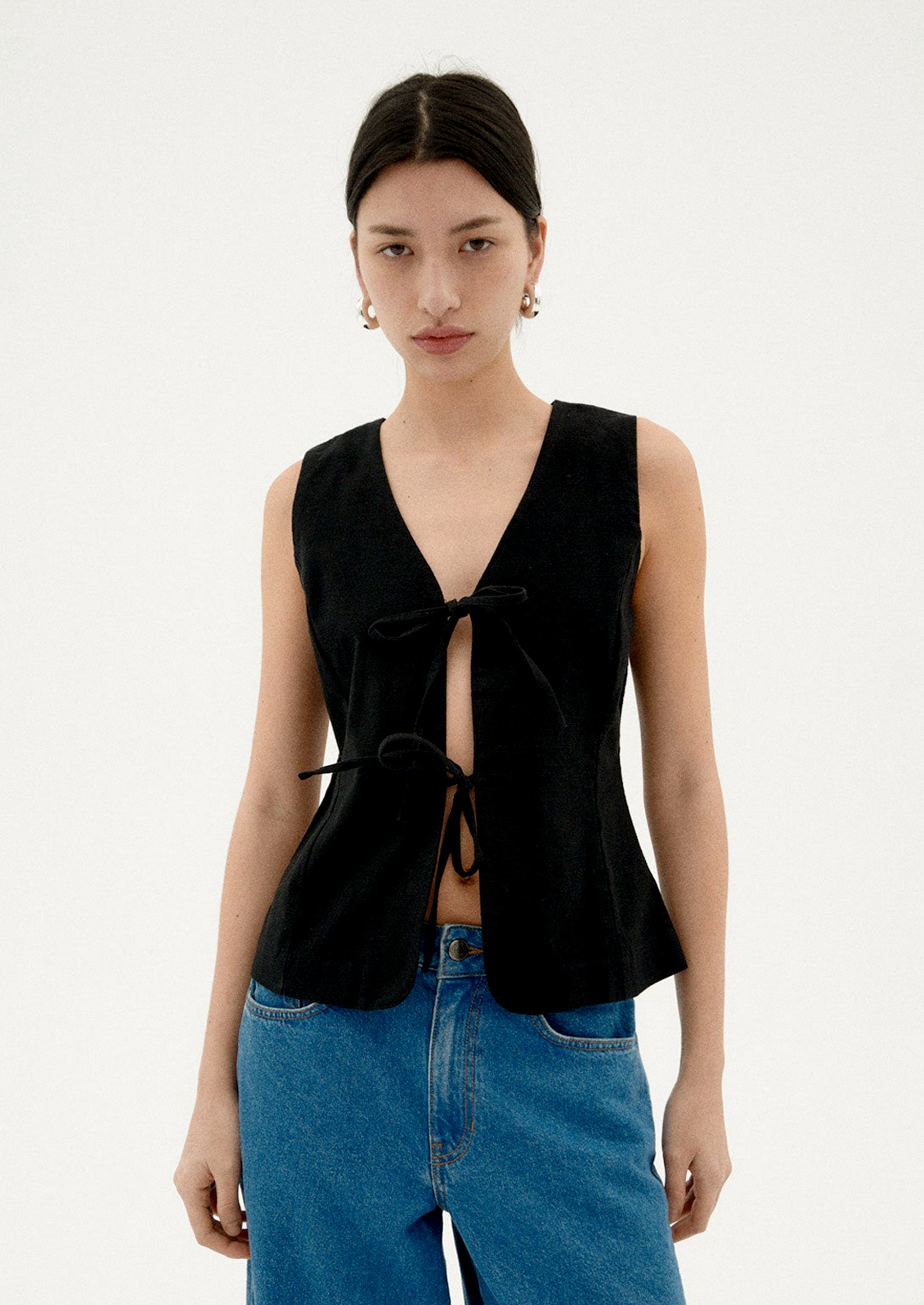 A woman wearing a black sleeveless top with front ties.
