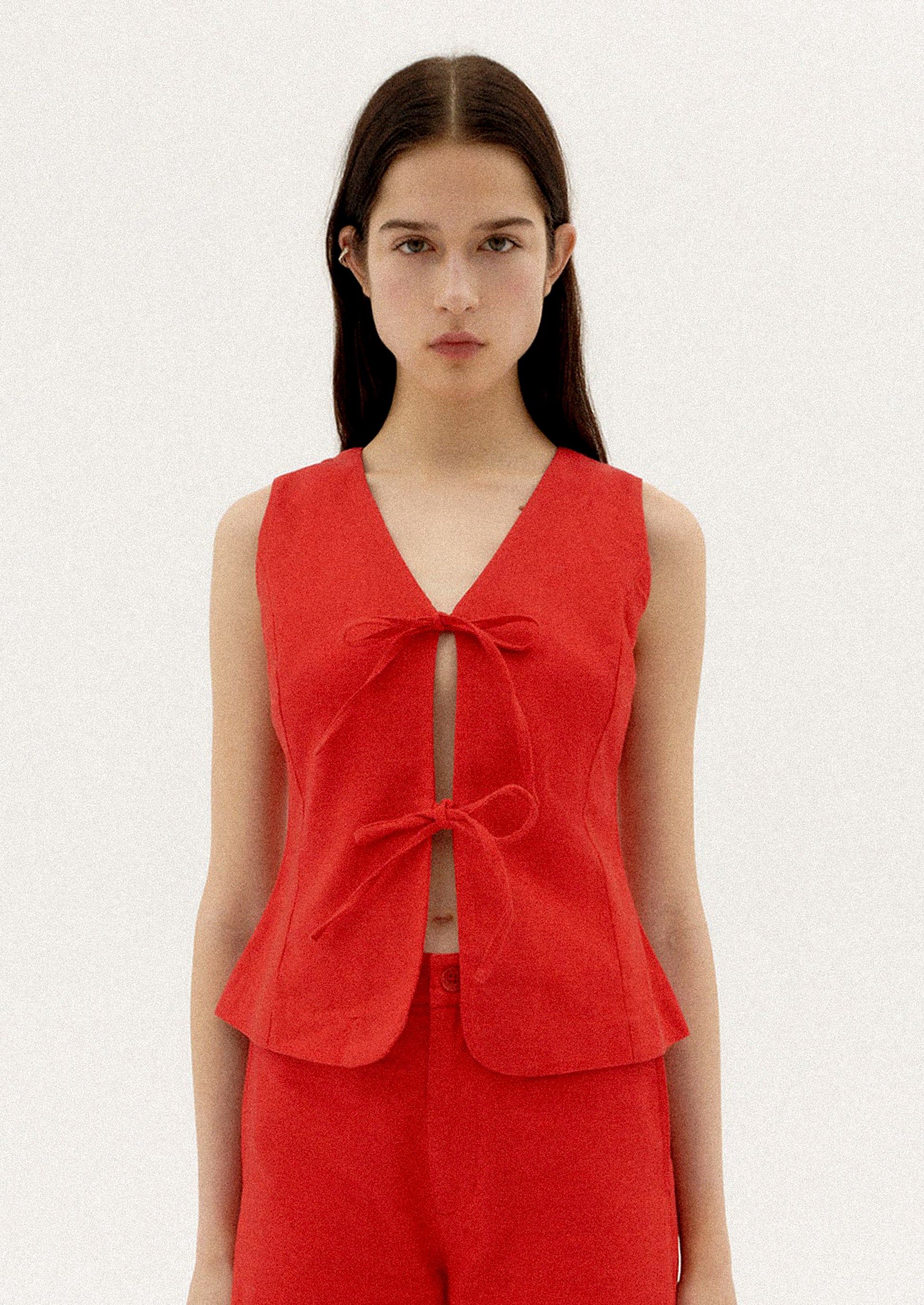A woman wearing a red sleeveless top with front ties.