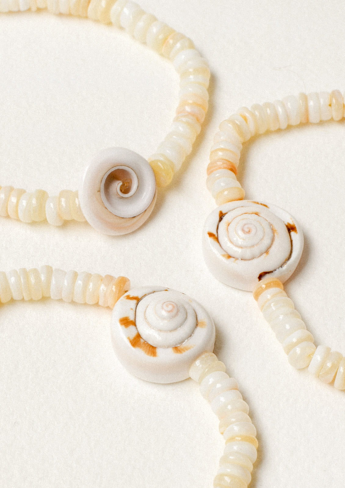 Three yellow beaded bracelets each with a genuine seashell pendant.