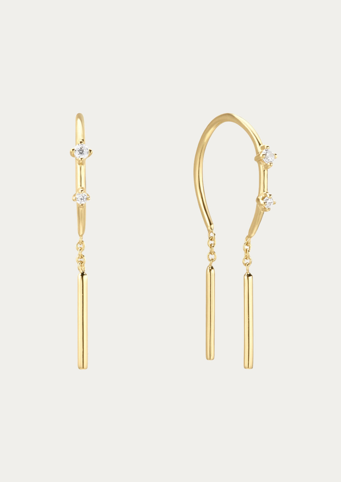 A pair of gold threader earrings adorned with two cubic zirconia gems on each earring on a white background.