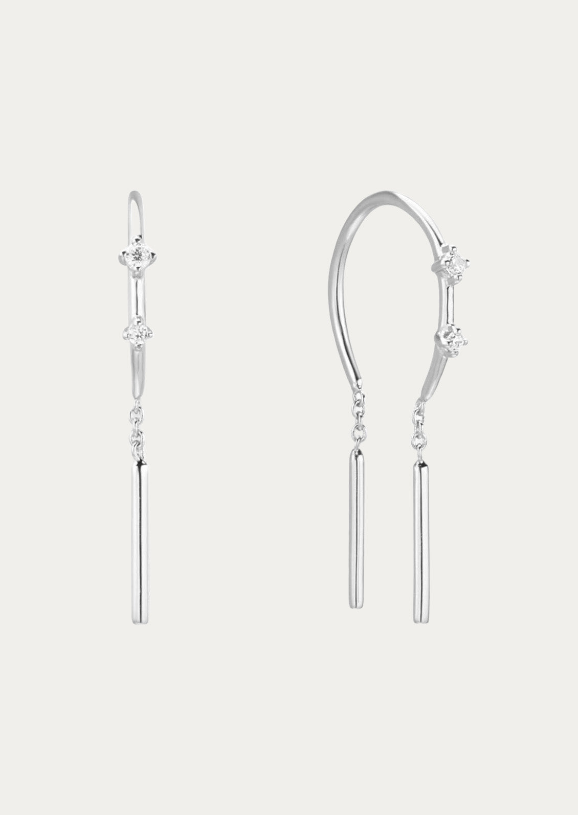 A pair of silver threader earrings adorned with two cubic zirconia gems on each earring on a white background.