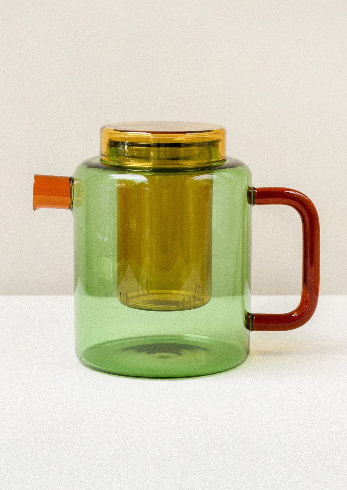 A multicolored glass teapot with an orange spout, red handle, and removable yellow tea steeper.
