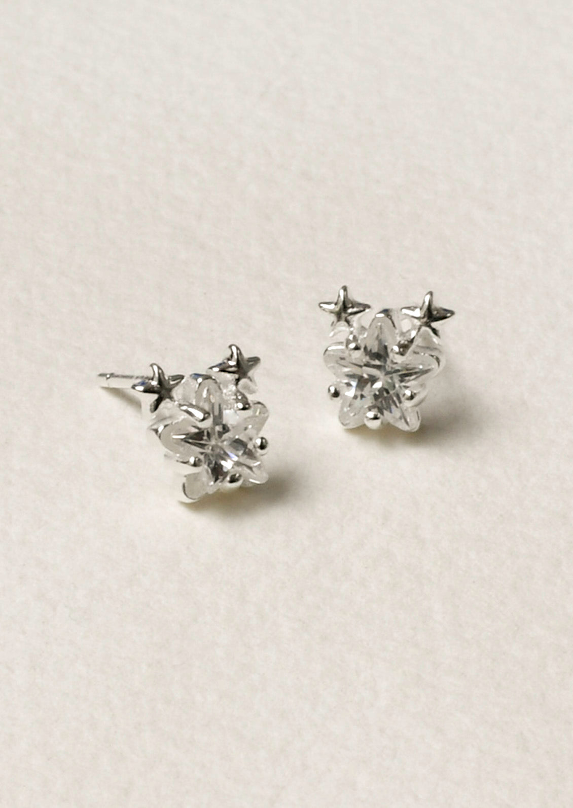 A pair of sterling silver star shaped cubic zirconia earrings with two tiny stars on the tops of each earring.