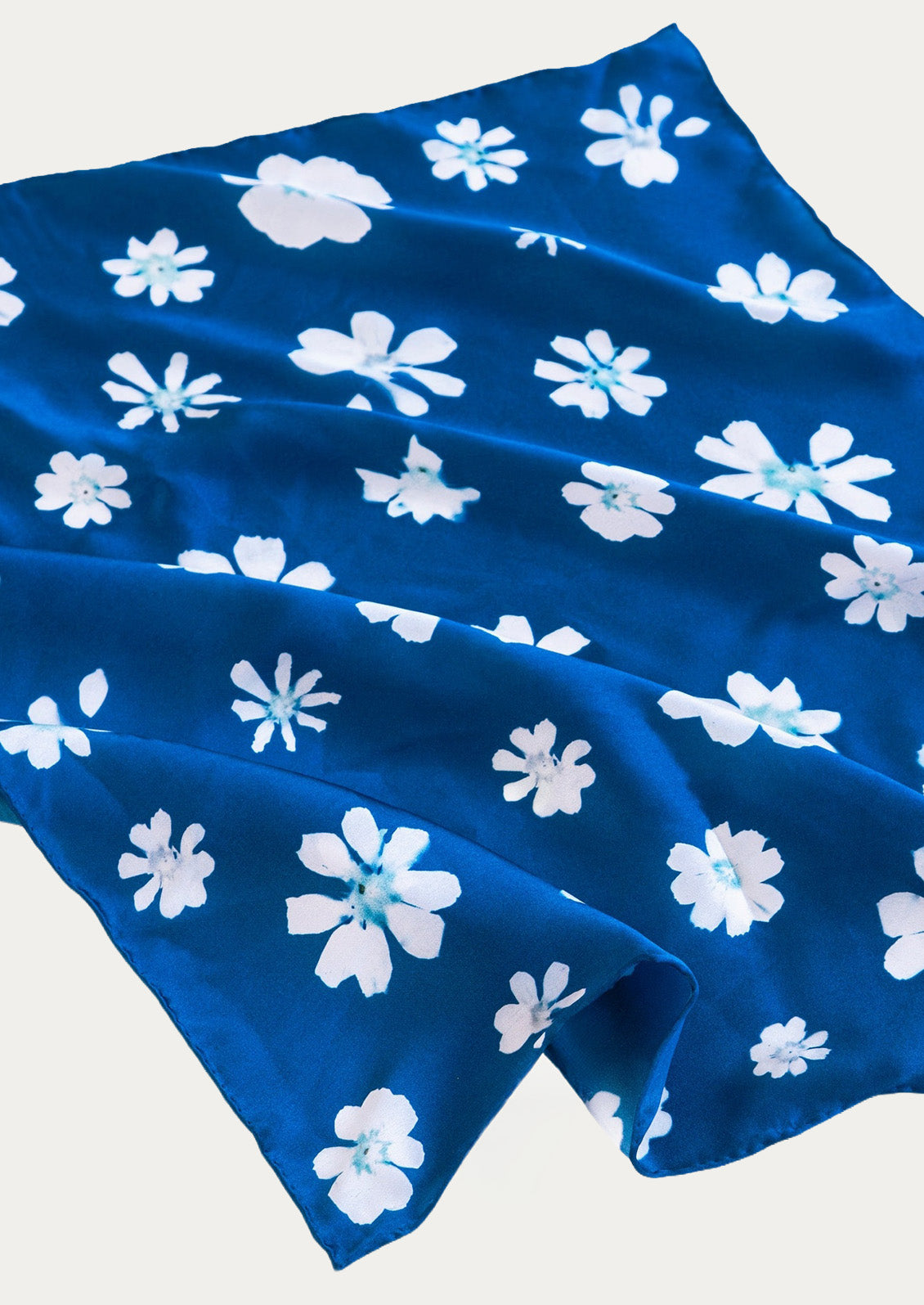 A blue square bandana with a floral cyanotype print.