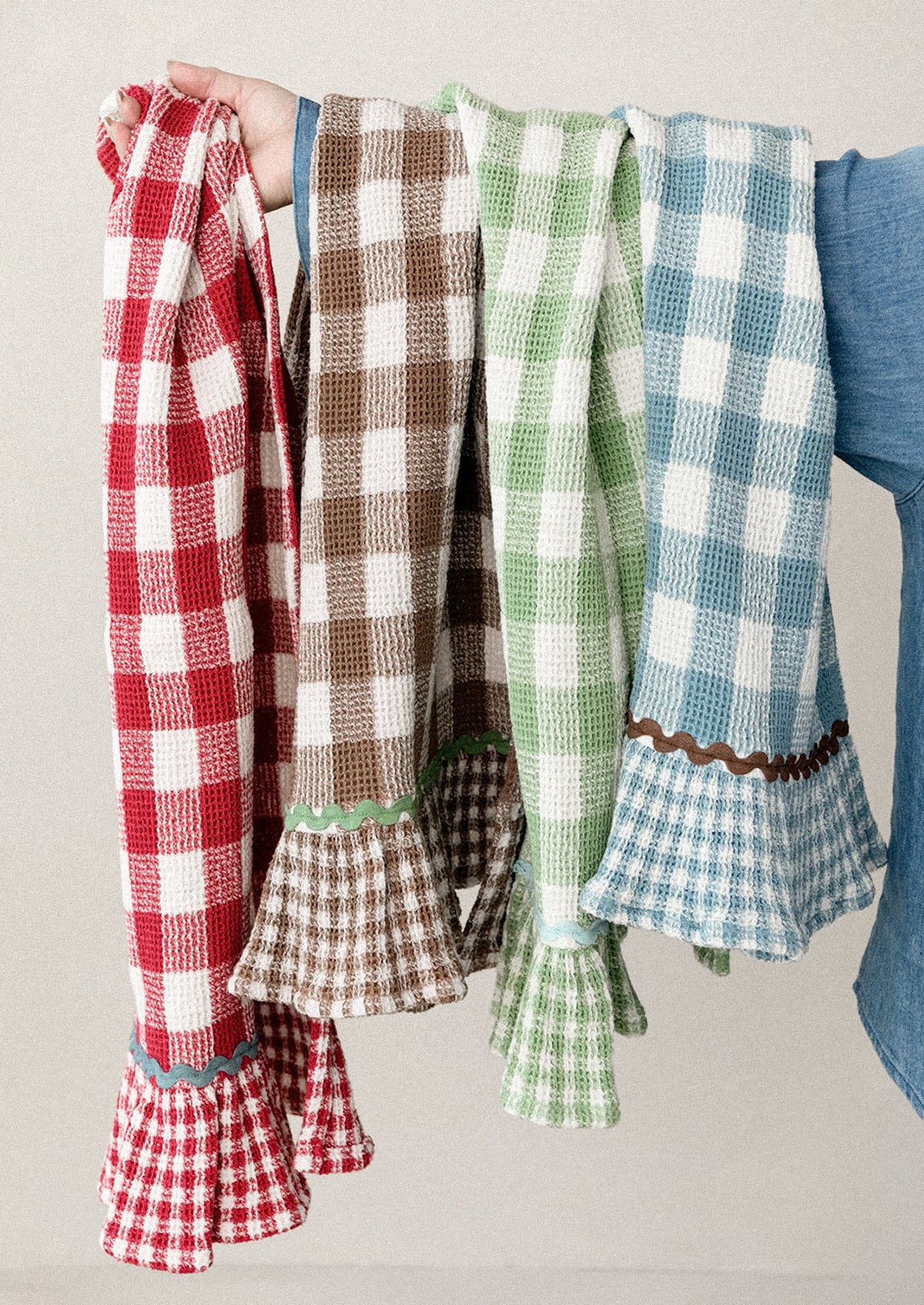 A person holding gingham tea towels in assorted colors.