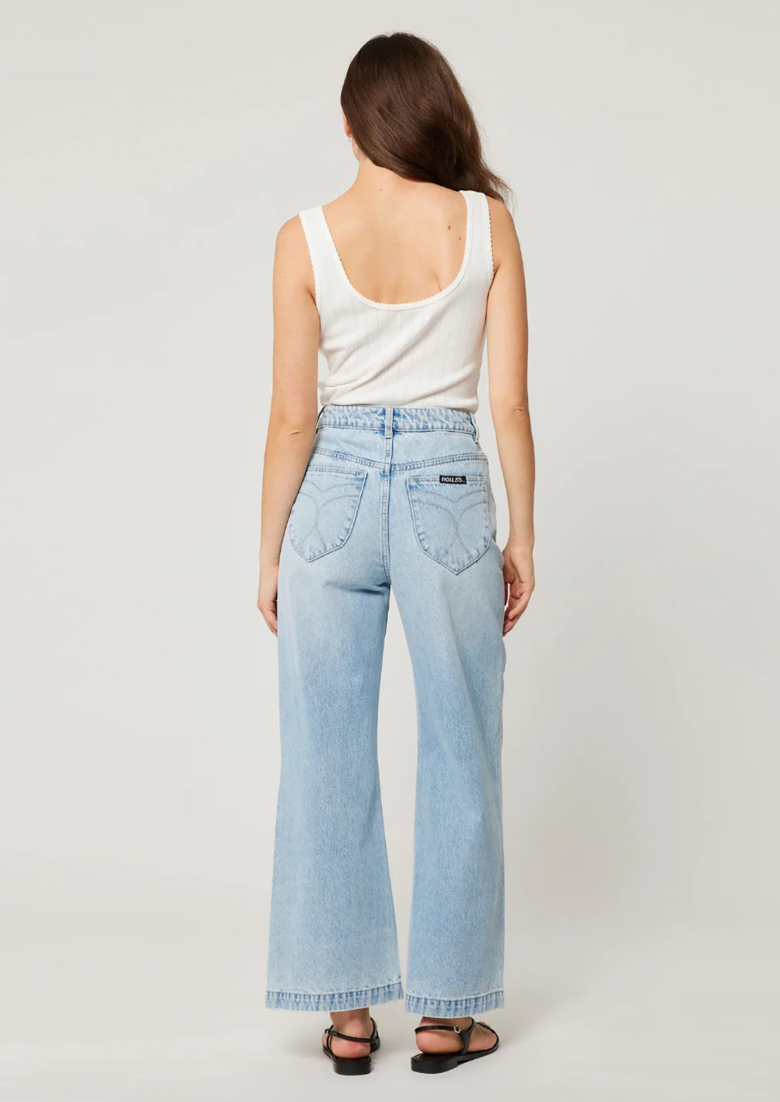 A person wearing a pair of light blue denim wide leg jeans with patch pockets at hips. 