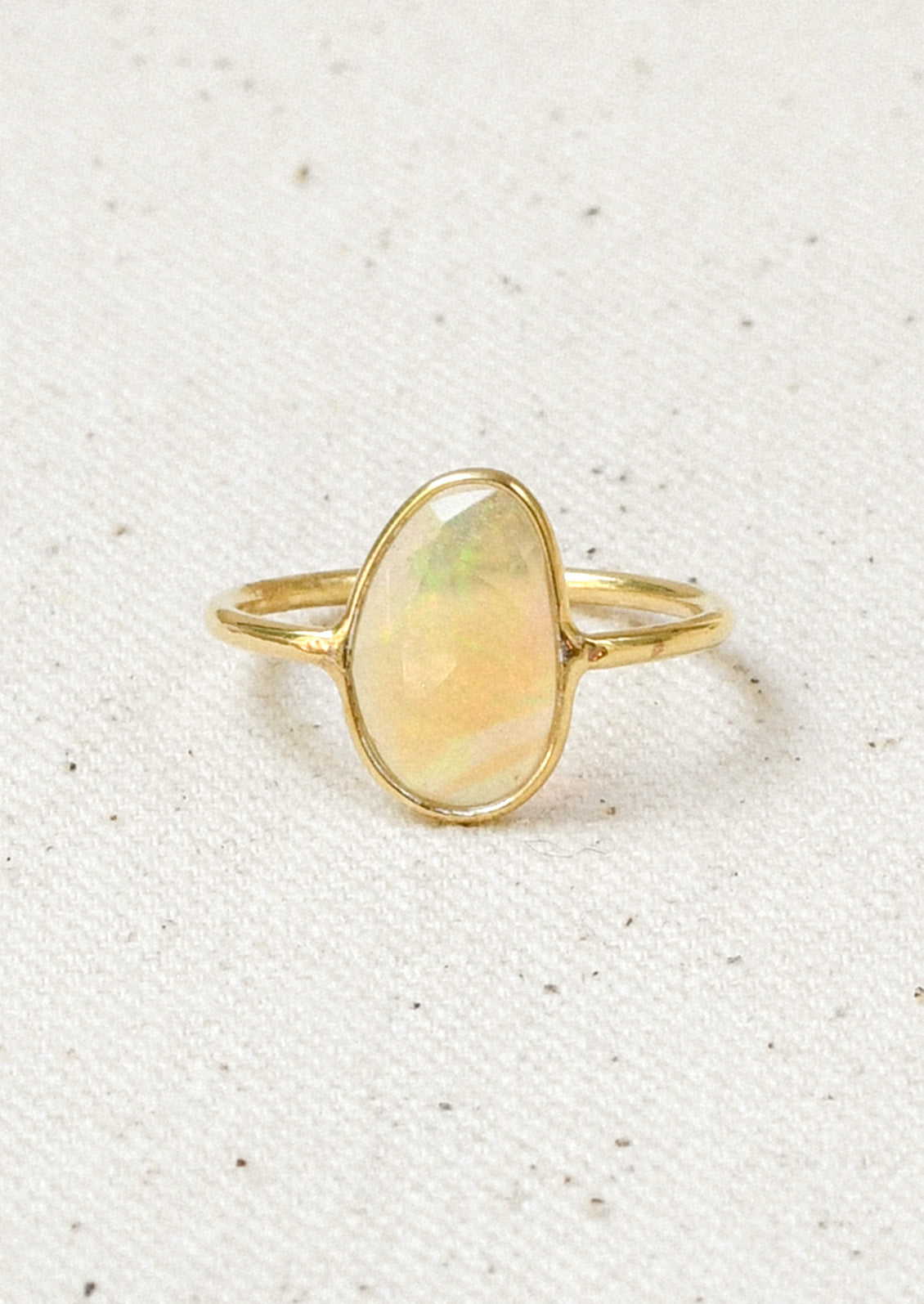 A gold ring with a natural Ethiopian opal bezeled in the center.