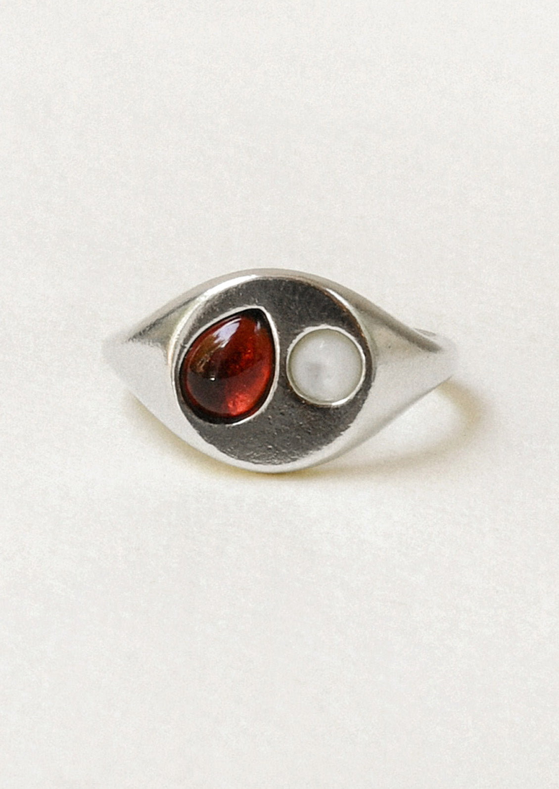 A sterling silver signet ring with a garnet gem and mother of pearl in the center.