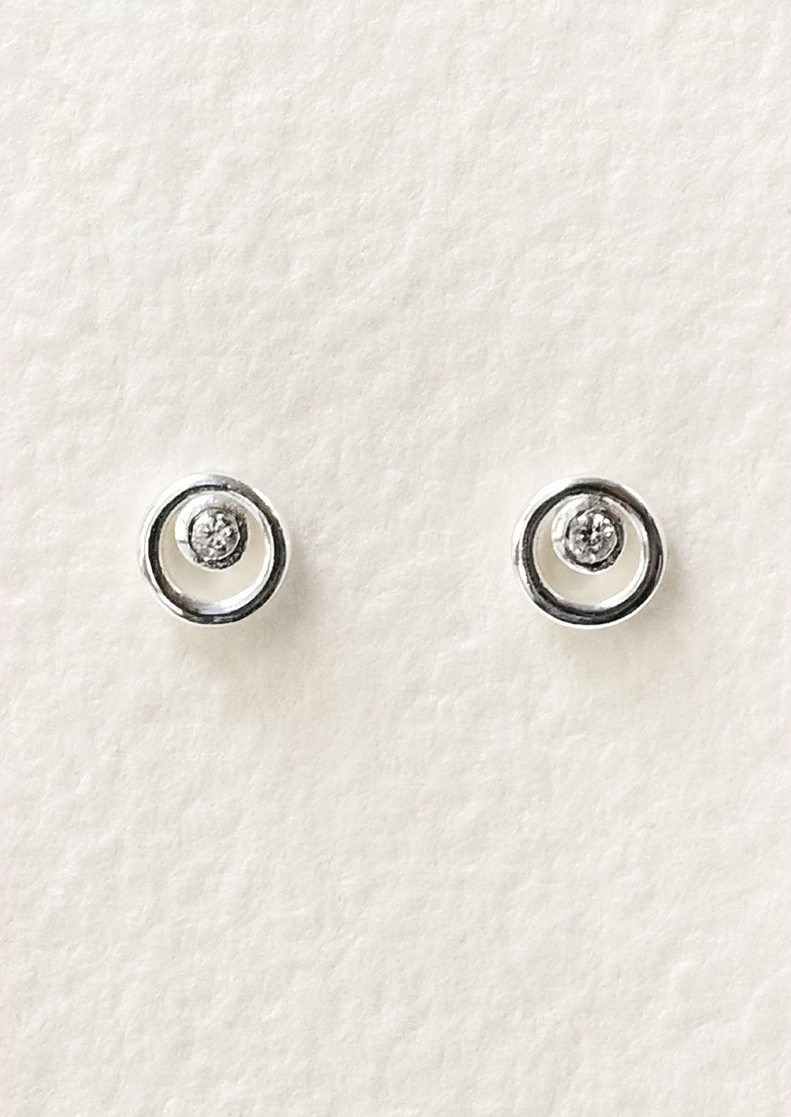 A pair of sterling silver circle stud earrings with a tiny crystal in the center.