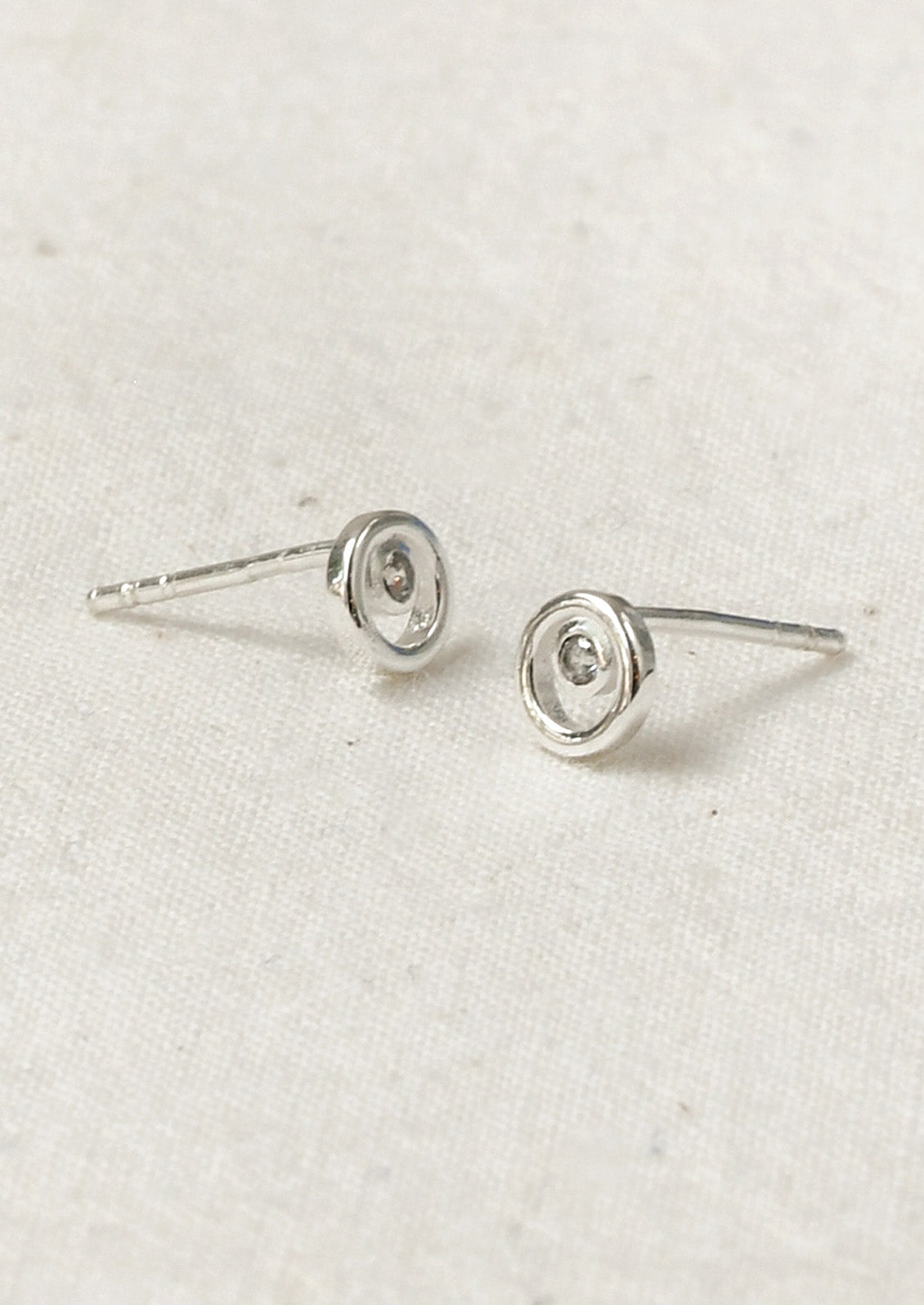 A pair of sterling silver circle stud earrings with a tiny crystal in the center.