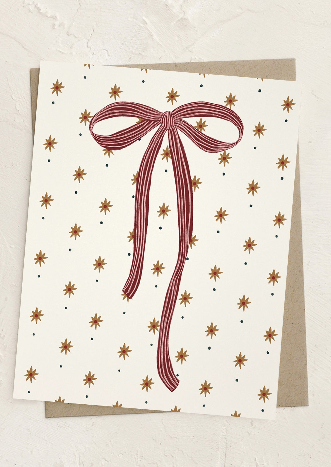 A greeting card with star pattern and a red striped bow.
