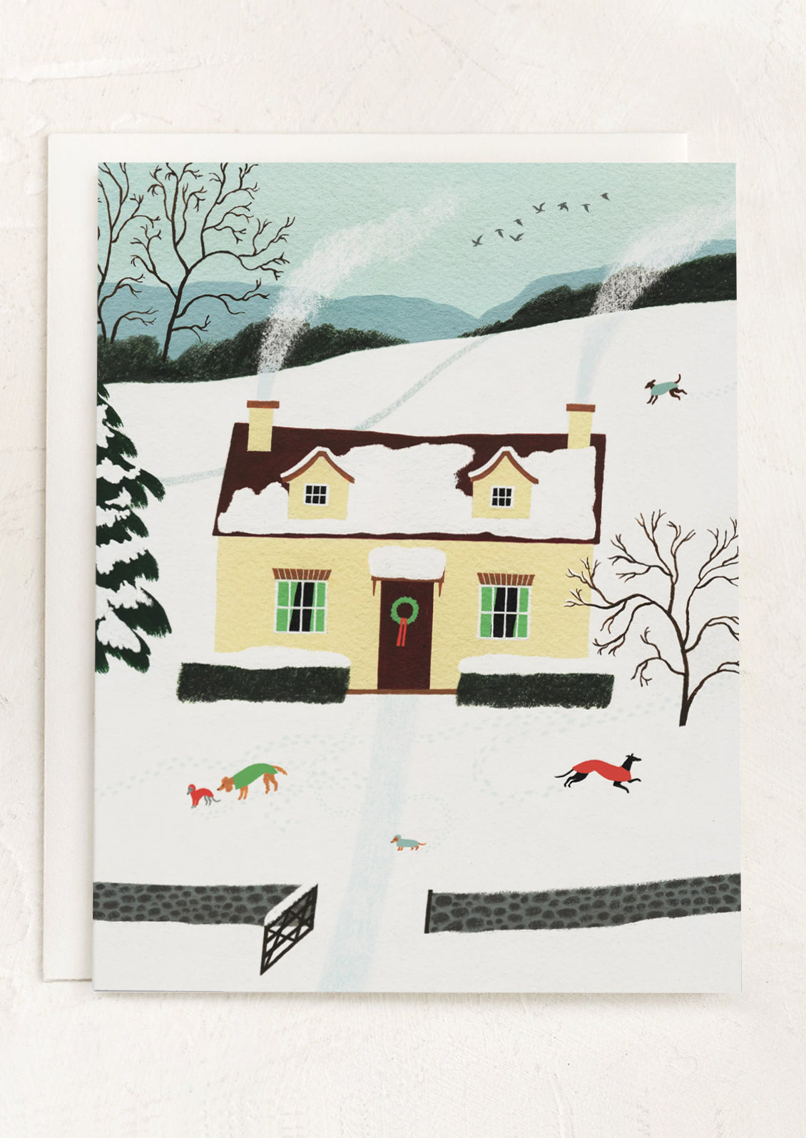 A greeting card with illustration of a house on a hill with a snowy, winter scene.