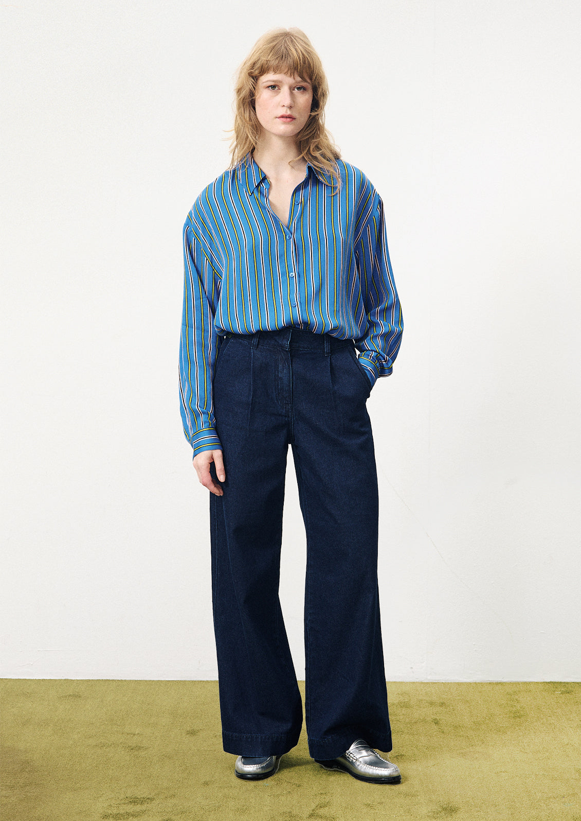 A woman wearing a pair of wide leg trouser style jeans in dark inky denim.