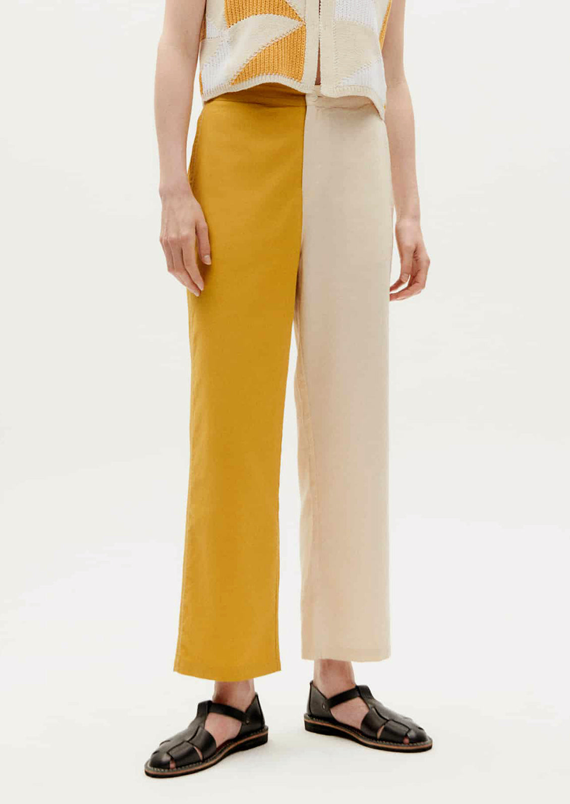 A pair of pants with one leg in yellow and one leg in cream.