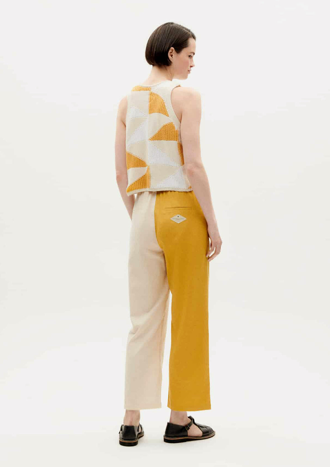 A pair of pants with one leg in yellow and one leg in cream.