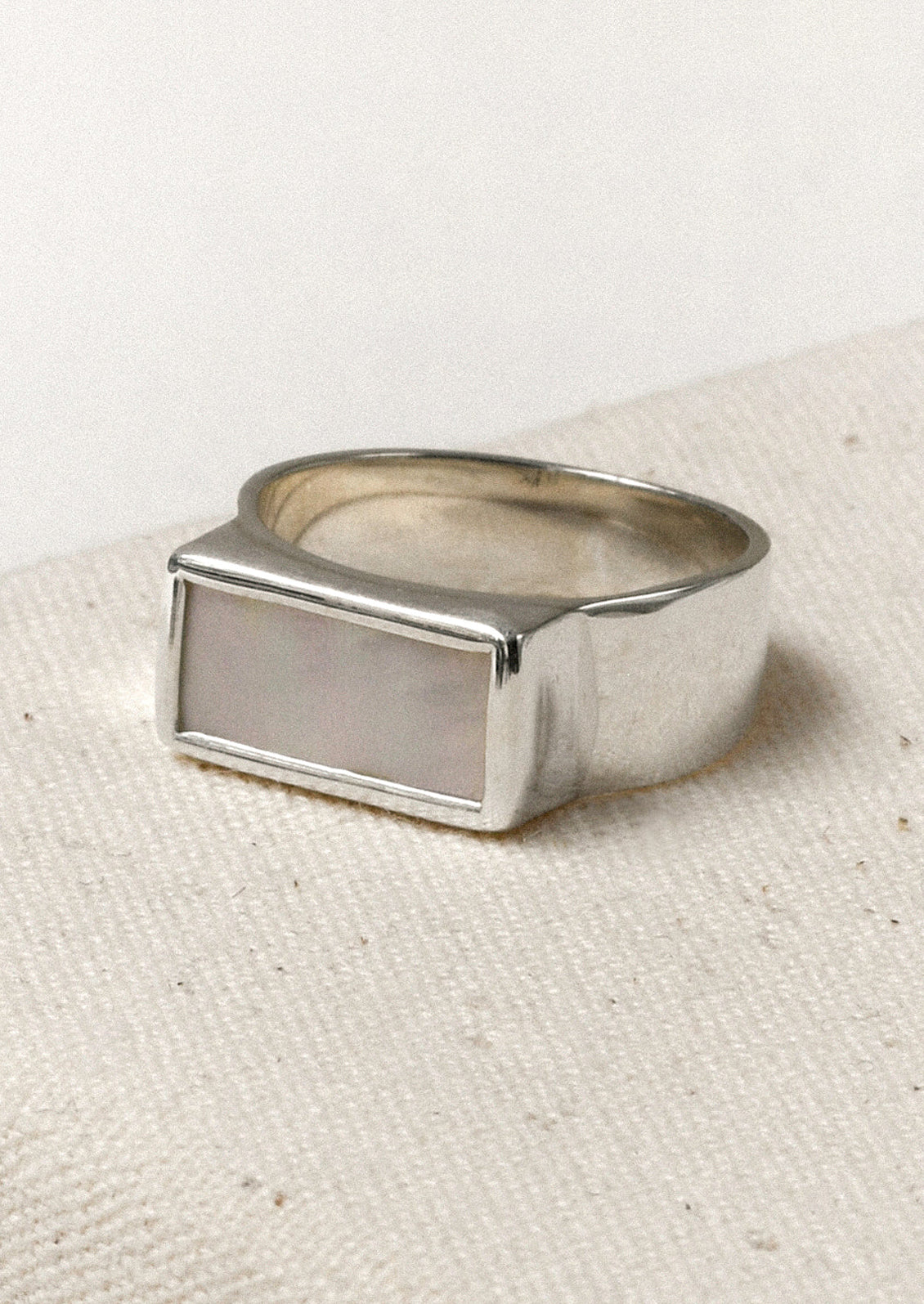 A sterling silver ring with a thick band and a rectangular mother of pearl set in the center.