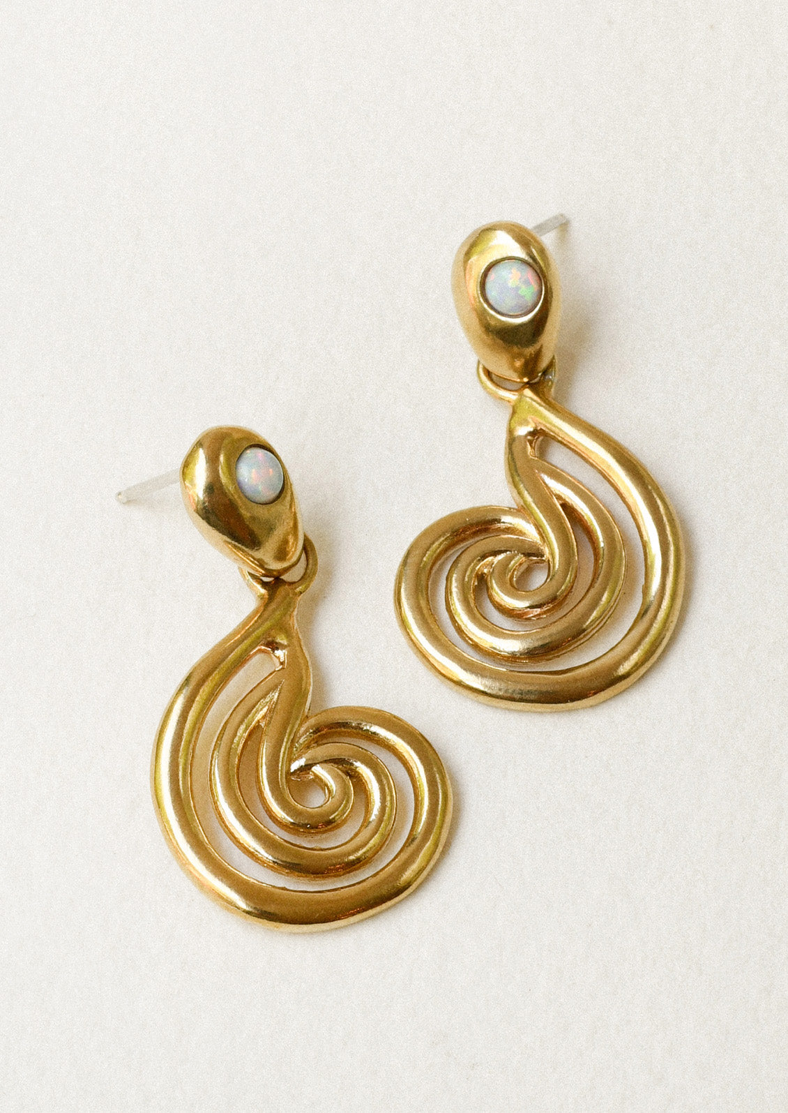 A pair of bronze earrings with a spiral design and opals at the top.
