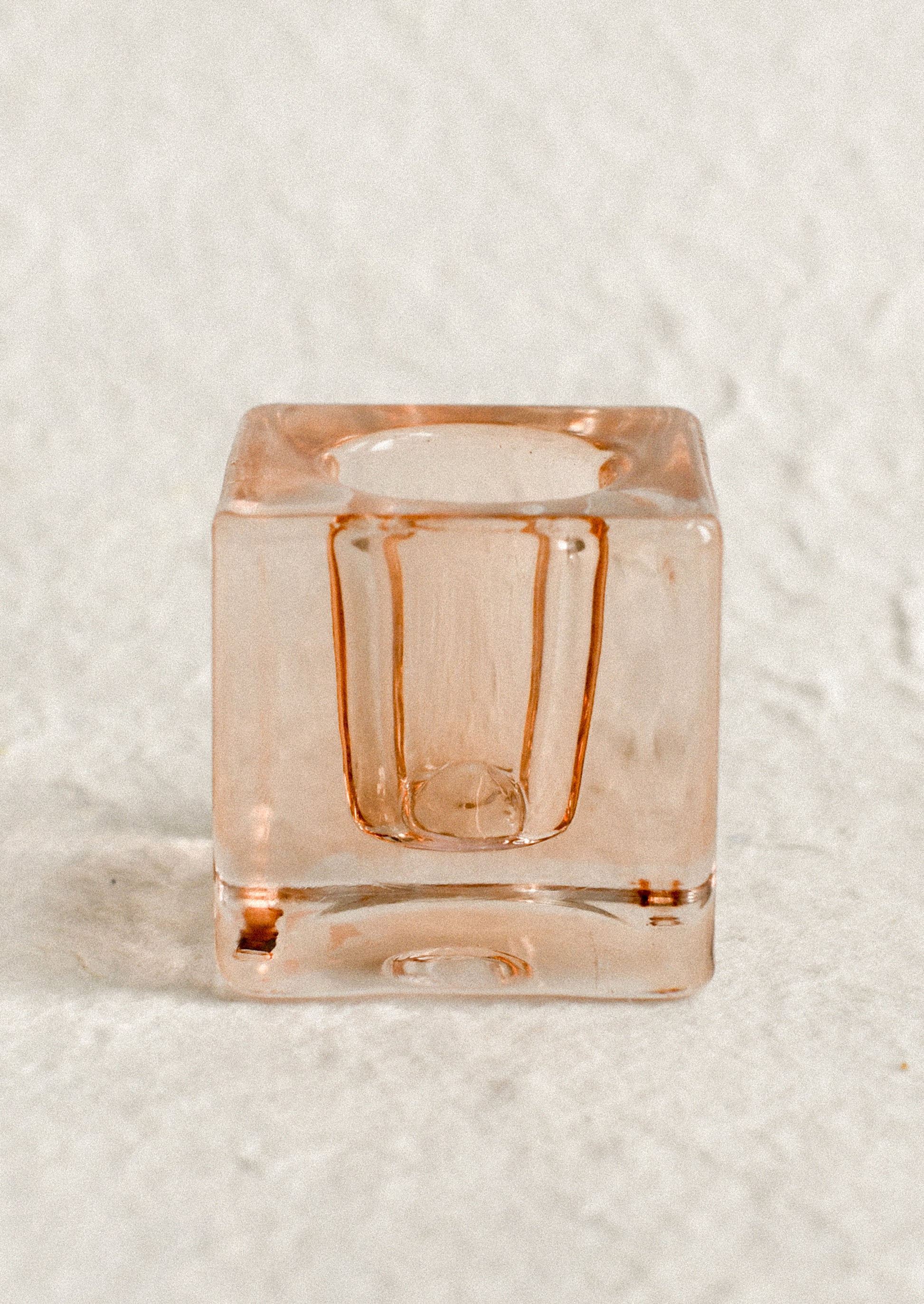 A cube-shaped slab glass candleholder in peach / short.