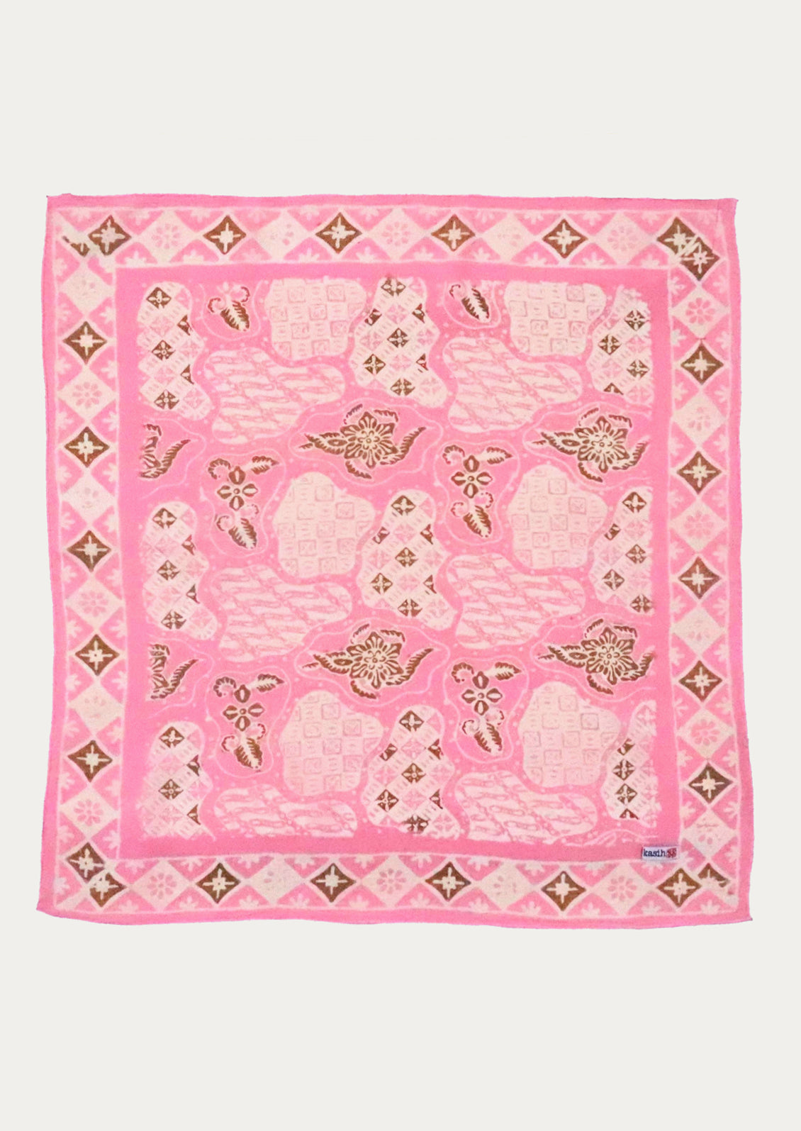 A pink scarf featuring a mosaic pattern with whiskey-tone printed motifs and a diamond border.