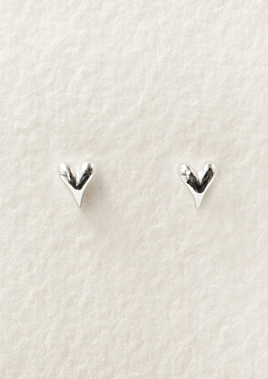 A pair of tiny sterling silver heart stud earrings.