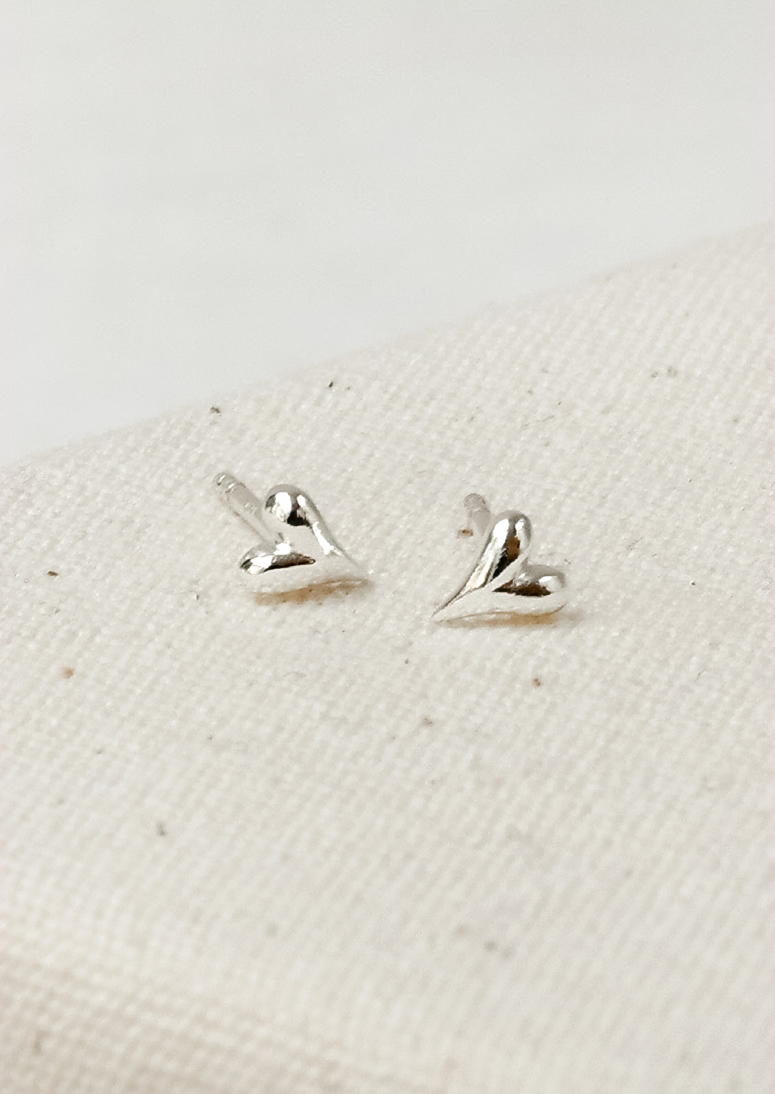 A pair of tiny sterling silver heart stud earrings.