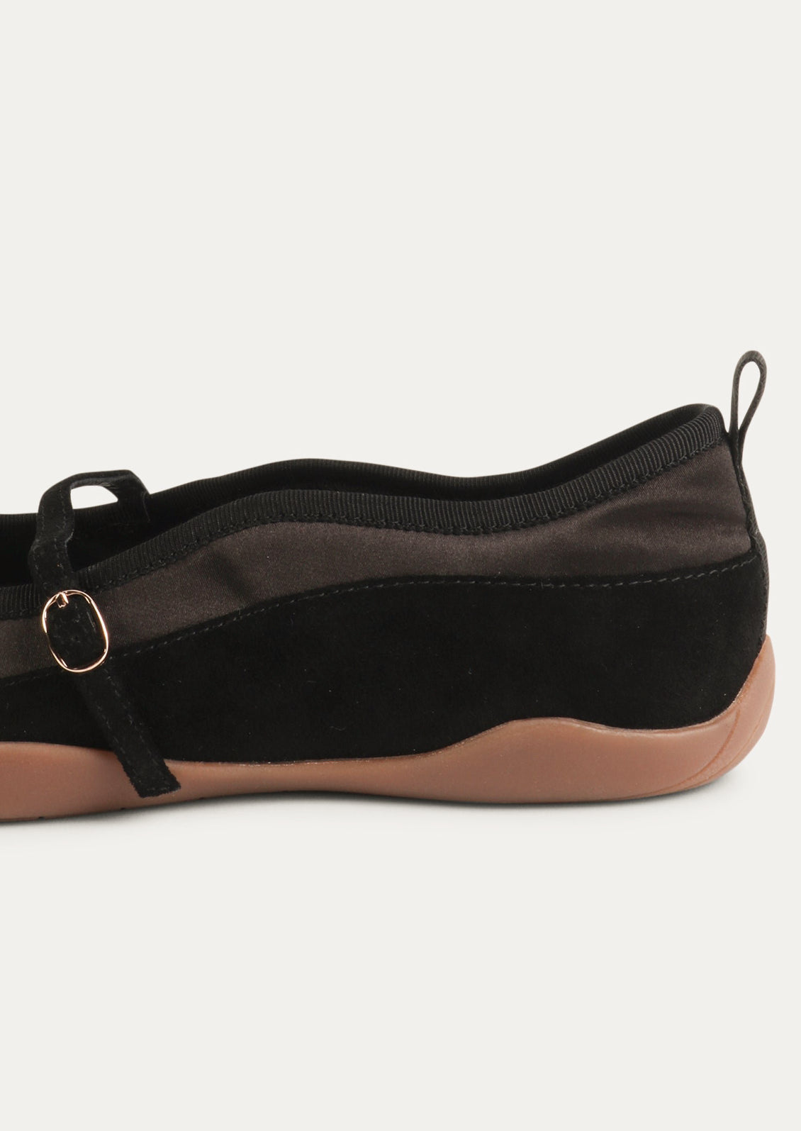 A black shoe that is part sneaker, part ballet flat mary jane. Suede/textile upper with a rubber gum sole.