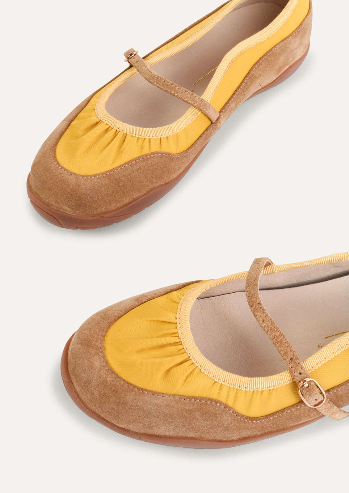 A pair of yellow and taupe shoes that are part sneaker, part ballet flat mary jane. Suede/textile upper with a rubber gum sole.