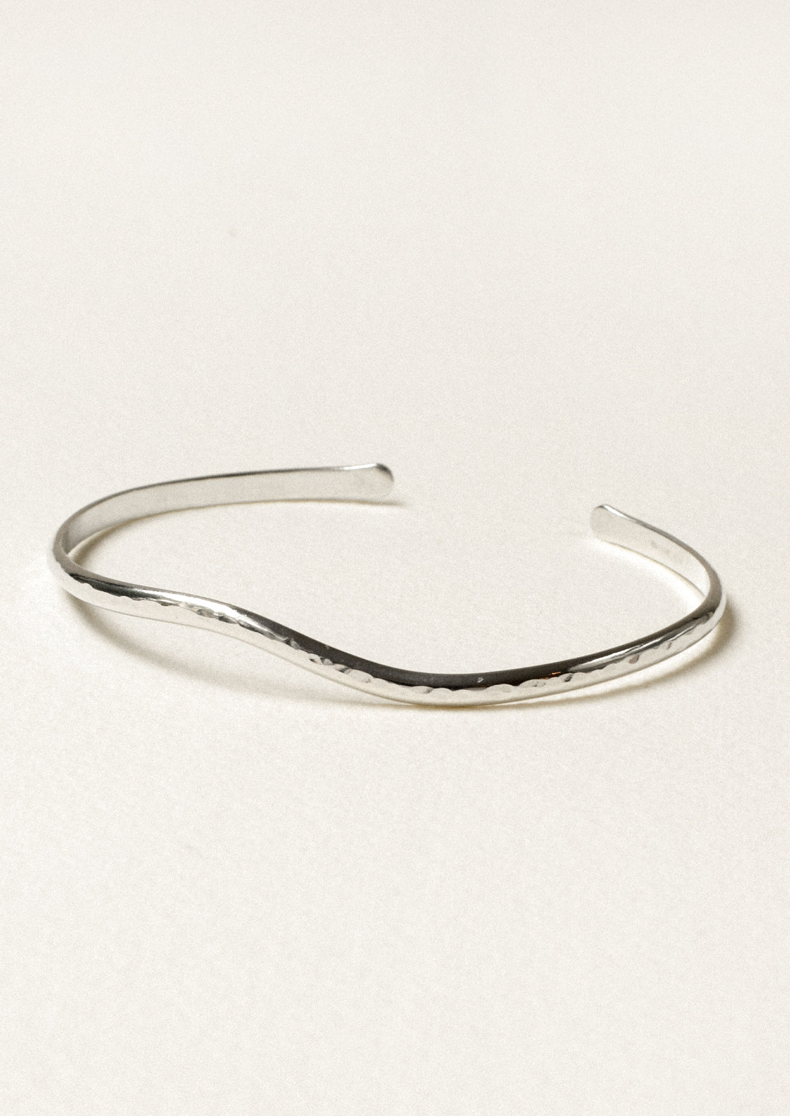 A minimal silver cuff bracelet with a wave-like design.