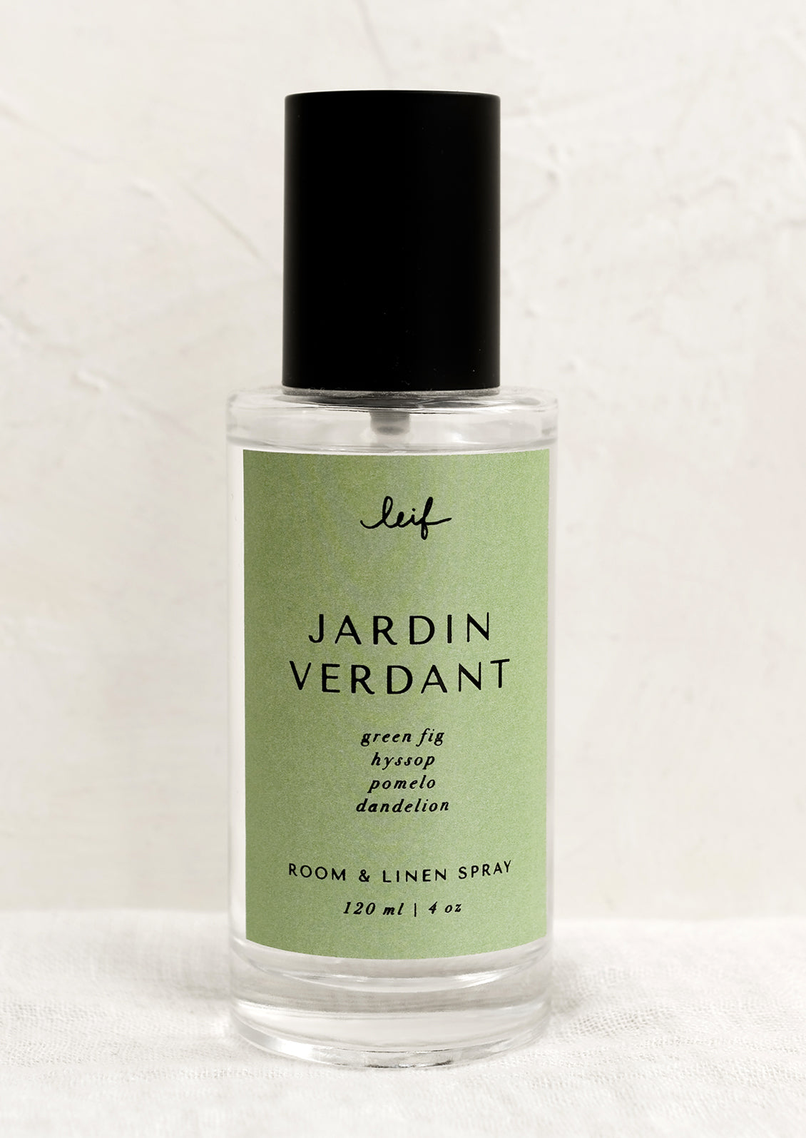 A room spray bottle with printed text on green label.