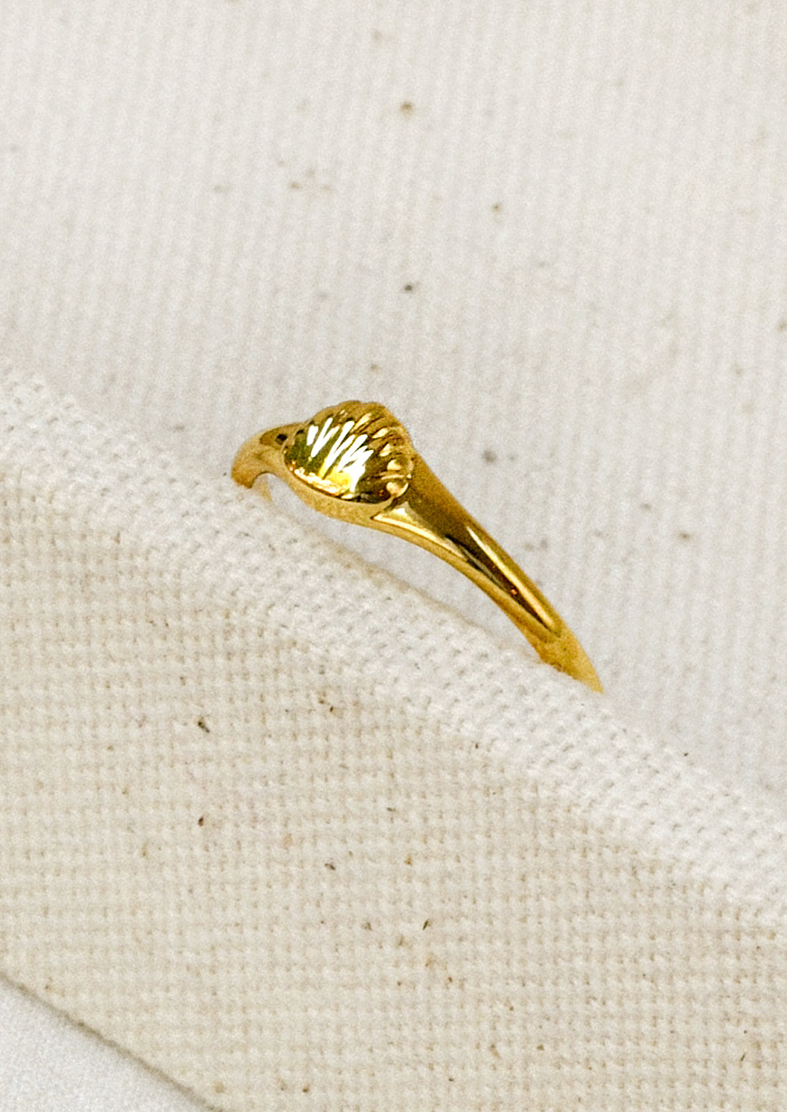 A gold ring with a tiny gold seashell on the front.