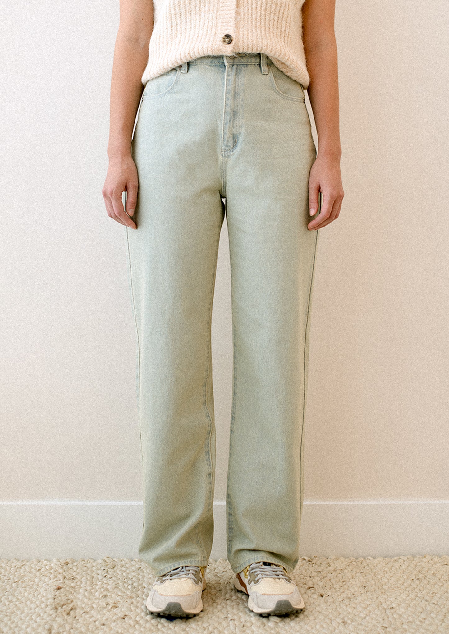 A woman wearing a pair of jeans in subtle green tinted light blue wash.