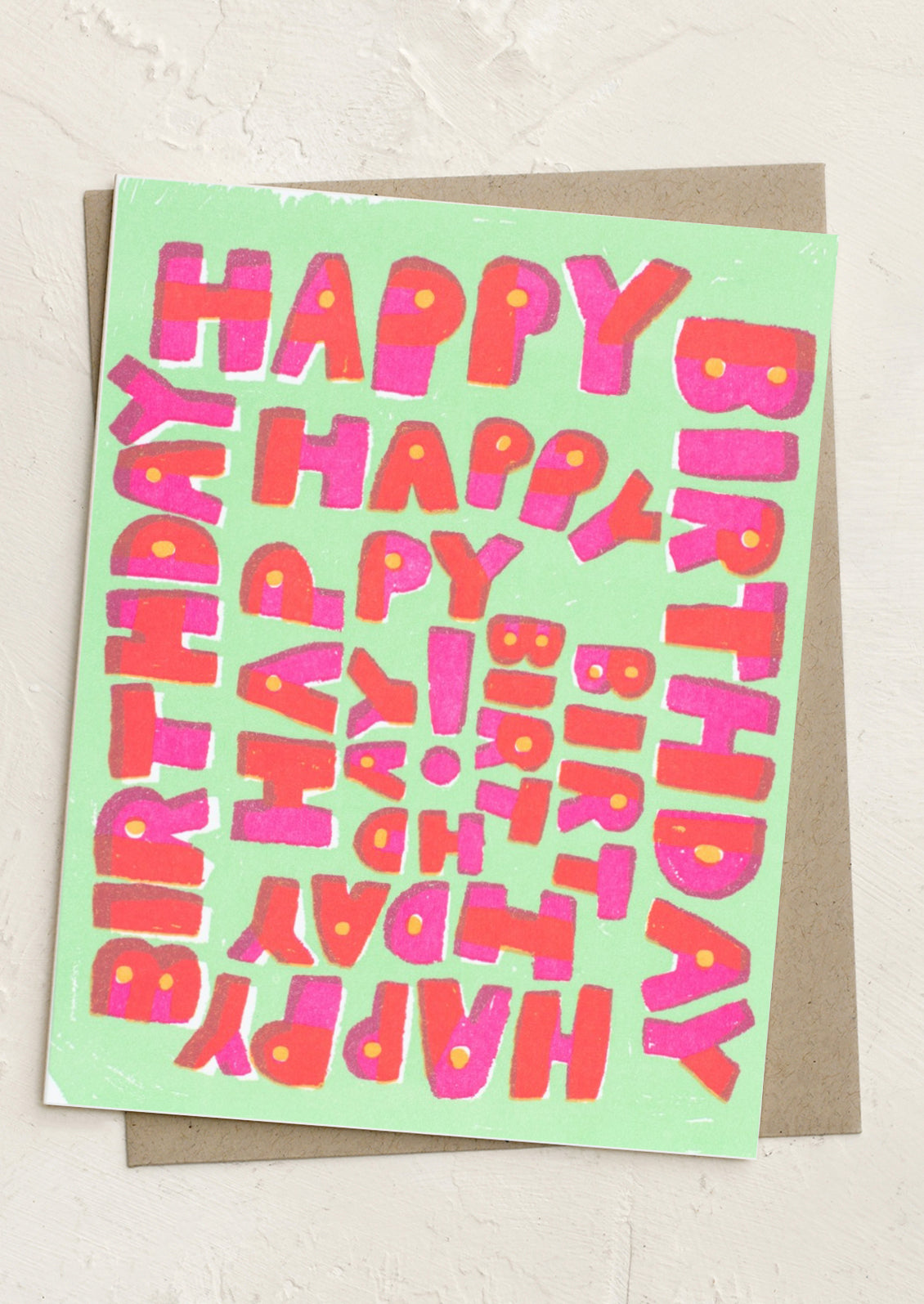 A mint green card with red and pink letters reading "Happy Birthday" repeatedly in a spiral shape.