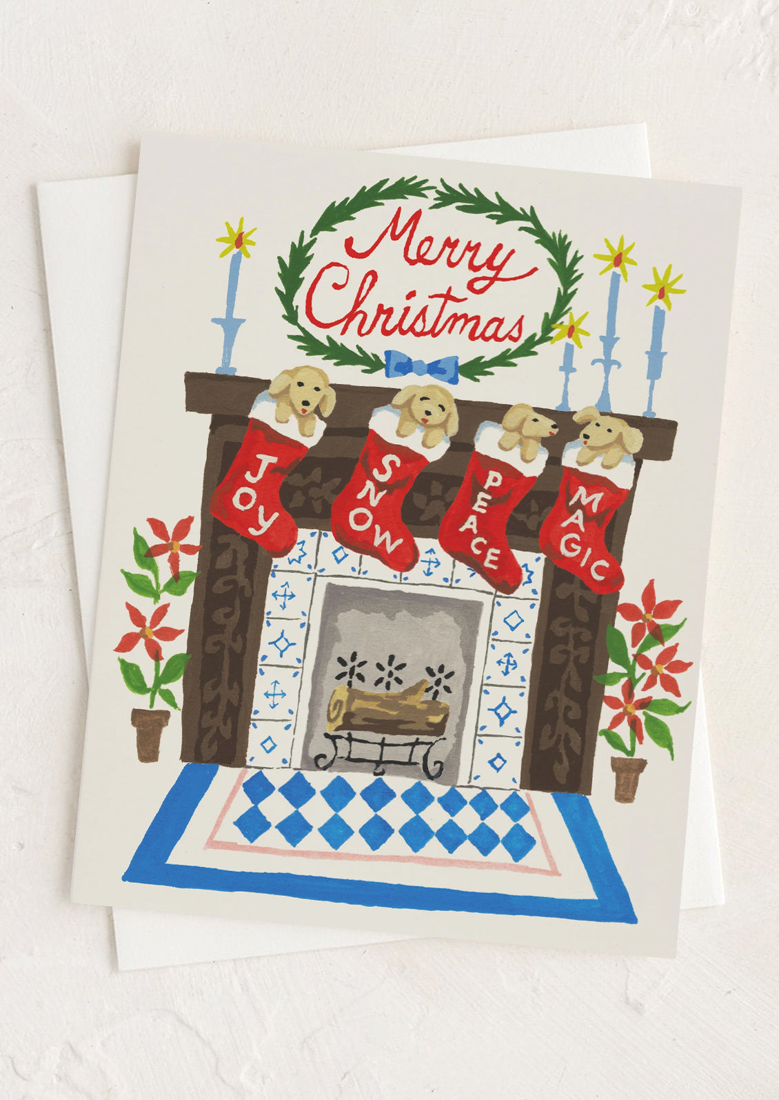 A greeting card with illustration of puppies in stockings by a fireplace, text at top reads "Merry Christmas".